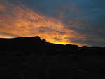 The desert sun setting behind the mountains